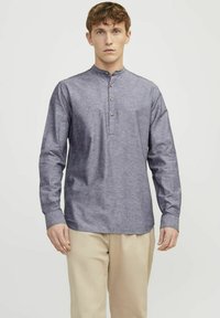Camicia a maniche lunghe da uomo in tessuto chambray azzurro chiaro. Caratterizzata da un colletto a banda stretto e una placca con tre bottoni. Texture liscia e vestibilità regolare.