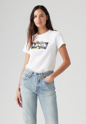 T-shirt en coton blanc avec un logo floral Levi's, accompagné d'un jean taille haute bleu clair avec des détails déchirés et une coupe classique.