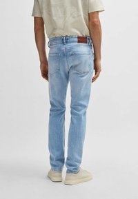 Jeans in denim azzurro chiaro con una vestibilità slim, dotati di una patch in pelle sullo orlo della vita e due tasche posteriori. Tessuto liscio, taglio dritto.
