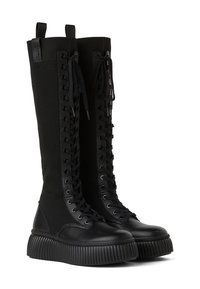 Czarne wysokie na kolano botki z prążkowanej tkaniny i skóry, z grubą platformą, sznurowaniem z przodu oraz uchwytem z tyłu.