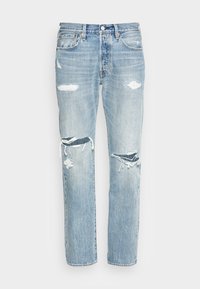 Ljust blå denimjeans med avslappnad passform, med slitna detaljer och stora hål vid knäna. Klassisk femficksdesign.
