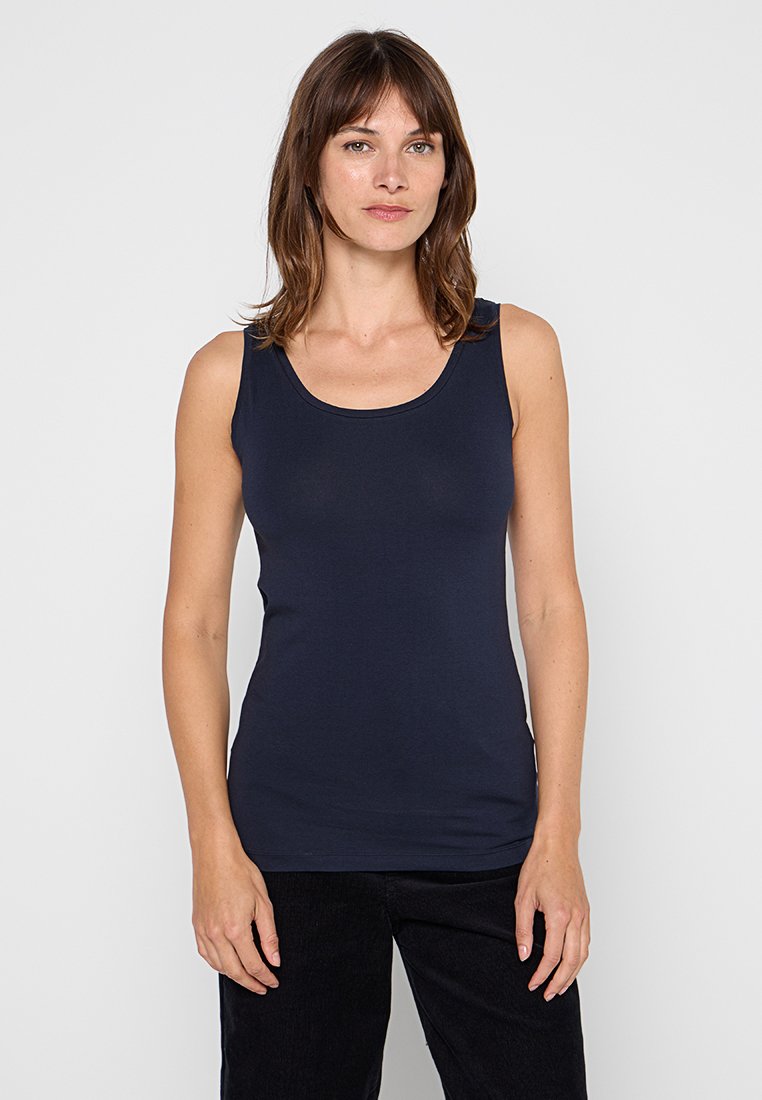 Navyblaues, ärmelloses Tanktop aus glattem Stoff mit rundem Ausschnitt und taillierter Form, getragen mit schwarzen Hosen.