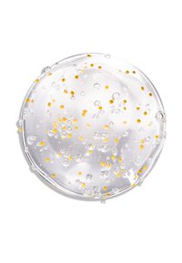 Gel transparent avec de petites perles jaunes et des bulles, forme circulaire, texture de surface brillante, sur un fond blanc.