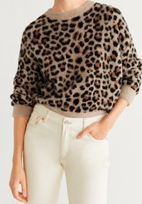 Suéter de estampado de leopardo borroso en beige, con manchas negras y marrones, cuello redondo y puños de canalé. Combinado con jeans blancos.