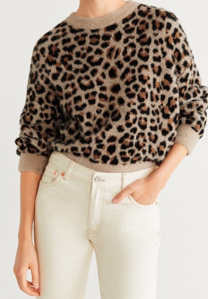 Suéter de estampado de leopardo borroso en beige, con manchas negras y marrones, cuello redondo y puños de canalé. Combinado con jeans blancos.