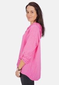 Rosa Kapuzenoberteil aus strukturiertem Material, mit umgeschlagenen Ärmeln, lockerer Passform und abgerundetem Saum.