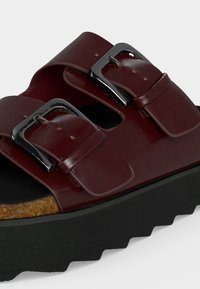 Sandale en cuir marron avec deux boucles argentées réglables, semelle intérieure en liège et semelle extérieure noire épaisse à rainures.