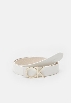 Witte leren riem met gouden "CK" gesp en beige binnenvoering bedrukt met herhaalde "Calvin Klein" tekst.