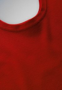 Tissu tricoté rouge en gros plan montrant un col rond et une couture fine sur un vêtement à texture lisse.