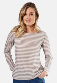 Langärmliges gestreiftes Hemd in hellbeige und Creme, aus weichem Stoff gefertigt, mit runder Ausschnitt und lässigem Schnitt, in blaue Jeans gesteckt.