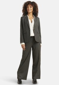 Gray pinstripe suit with a tailored blazer and wide-leg trousers, paired with a white button-up shirt. Boots complete the outfit.