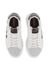 Λευκά αθλητικά παπούτσια με γκρι καπάκια από σουέτ στα δάχτυλα, διακριτικά στοιχεία από δίχτυ και μαύρες λεπτομέρειες. Διαθέτουν κορδόνια και μαύρες ταμπελίτσες με λογότυπο στη φτέρνα.