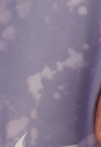 Purple athletic fabric with a smooth texture, featuring a subtle tie-dye pattern and a white logo accent in the lower corner.