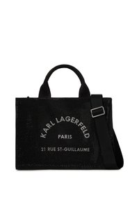 Sac fourre-tout noir présentant une surface texturée, un logo blanc centré, des poignées doubles et une sangle amovible et réglable.