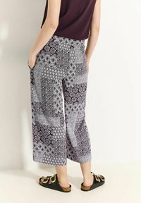 Zwart-witte gemusterde cropped broek met een mix van geometrische en bloemenpatronen, voorzien van zijzakken en een losse pasvorm.