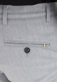 Grå byxor med en strukturerad tygkvalitet, som har en bakficka med en svart knapp och randig detalj. Rena linjer och skräddarsydd passform.