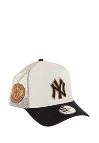 Lastcap mit weißer Vorderseite und schwarzem Schirm, ausgestattet mit einem geprägten braunen Lederpatch und einem erhabenen schwarzen Logo auf der Vorderblende. Mit Netzseiten.