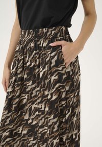 Zwarte en beige gestipte rok met een golvend ontwerp, elastische tailleband en zijzakken. Gemaakt van zachte, lichte stof.
