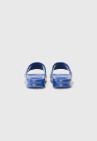 Blue slip-on sandals made of soft material with open backs, rounded shapes, and textured insoles, offering a minimalistic design.