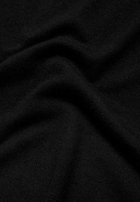 Gros plan sur un tissu noir lisse et doux avec des plis subtils et une fine texture tricotée.