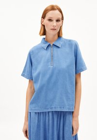 Blaues Jeansoberteil mit kurzen Ärmeln, einem Kragen und einem Reißverschluss vorne. Hat einen lockeren Schnitt und eine weiche Textur, geeignet für Freizeitkleidung.