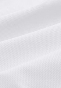 Tissu blanc lisse avec un tissage texturé subtil et des plis doux créant des ombres et des éclats délicats.