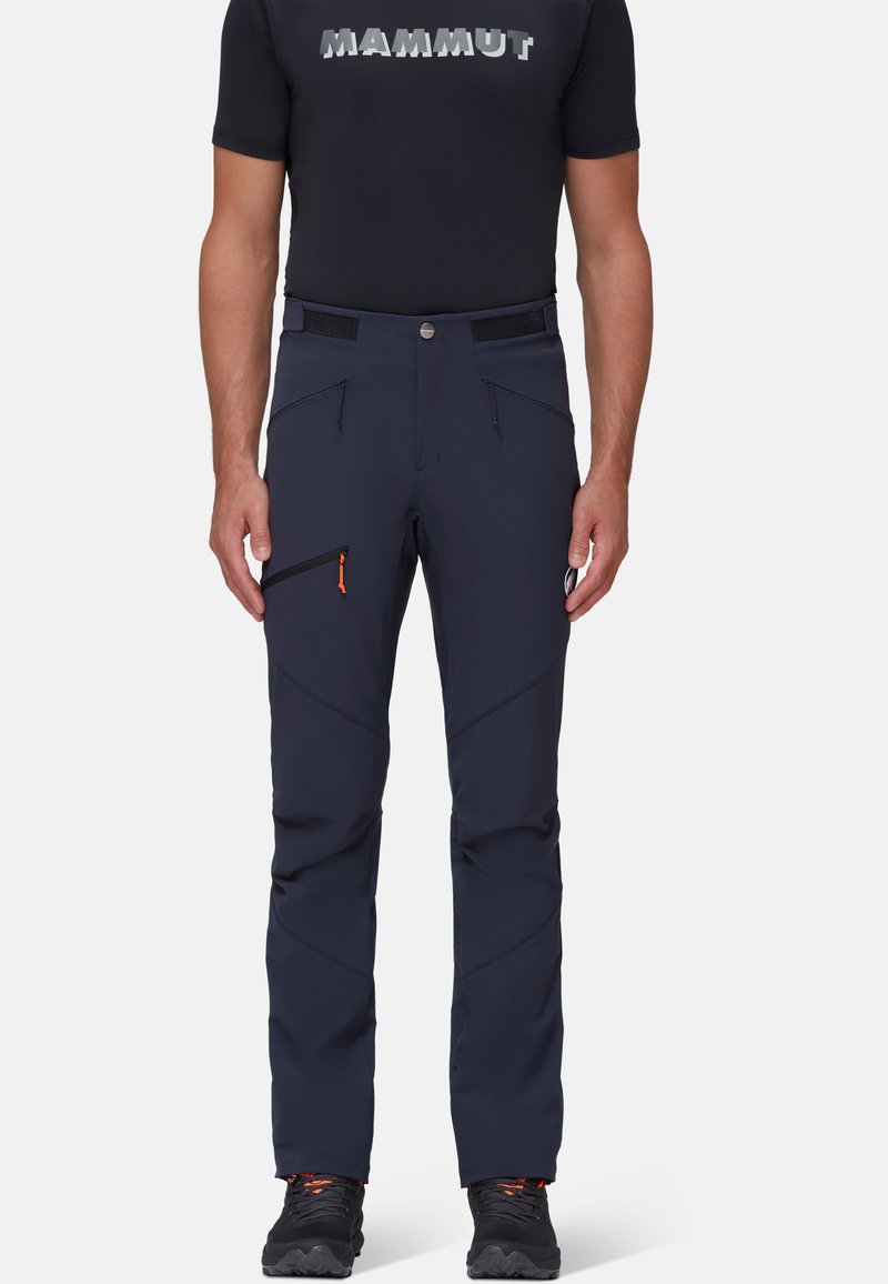 Navy wandelschoenen met een slim fit, gemaakt van rekbare stof. Beschikt over twee voorste ritszakken en een schuine zijrits zak met oranje accenten.
