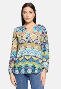 Bluzka z długim rękawem w wielokolorowe wzory, z dekoltem w kształcie litery V, ozdobiona geometrycznymi wzorami w odcieniach niebieskiego, zielonego i brązowego. Lekka, przejrzysta tkanina.