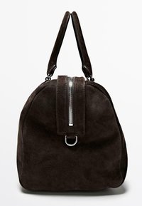 Tmavě hnědá semišová kabelka s dvojitými uchy, středovým stříbrným zipem a kovovým kroužkem na přední straně na bílém pozadí.