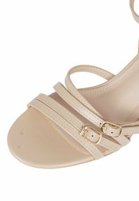Sandalini beige con tacco alto, con cinturini, pelle liscia, doppi dettagli con fibbie e punta rotonda.