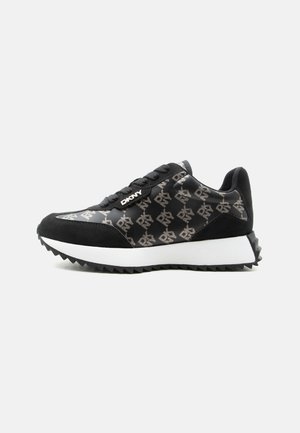 Baskets basses noires avec semelle blanche, décorées de logos "DKNY" répétés et lacets noirs sur fond gris clair.