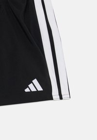 Shorts de sport noirs avec des rayures blanches sur les côtés. Présente un logo triangulaire blanc près de l'ourlet, mettant en avant un design sportif.