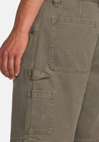 Shorts cargo khaki dintr-o țesătură texturată, cu multiple buzunare și un tab lateral pentru ajustare. Cusături vizibile și un croi clasic.
