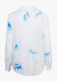 Camicia bianca con motivi tie-dye blu, maniche lunghe, polsini con bottone e colletto classico con yoke sul retro e due pince posteriori.