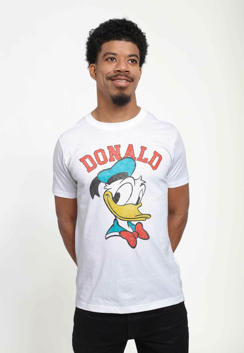 Biała bawełniana koszulka z kolorową grafiką Kaczora Donalda, z czerwoną napisanym powyżej słowem "DONALD". Wzór jest nadrukowany sitodrukiem.
