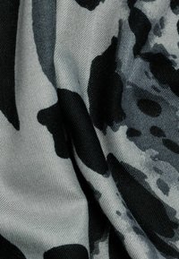 Schwarz-weißer Stoff mit einem glatten Textur, der große abstrakte Formen in einem kontrastierenden monochromen Design zeigt.