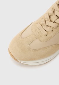 Baskets beige avec une tige en daim et des accents en mesh. Caractéristiques : bout rond et fermeture à lacets. Semelle intermédiaire blanche et semelle extérieure en caoutchouc texturé.