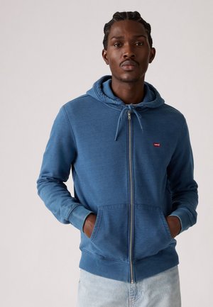Blauwe rits-hoodie van zacht materiaal, uitgerust met een trekkoordhoody, zijzakken en een klein rood Levi's logo op de borst.