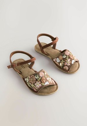 Sandales brunes à bout ouvert et avec une lanière à la cheville ; le tissu présente des broderies florales multicolores et une semelle intérieure douce et texturée.