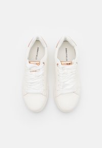 Hvite joggesko med et glatt læraktig materiale. Har flate lisser, roségull detaljer og små perforeringer på sidene.