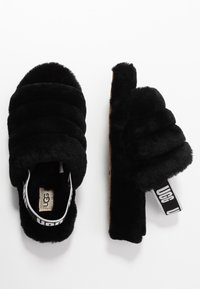 Pair of black plush UGG slippers with padded straps and a branded elastic heel strap, shown from top and side views on white background.