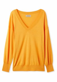 Ljusorange V-ringad tröja i mjukt stickat material. Har långa puffärmar samt ribbade mudd och f åll för en avslappnad passform.