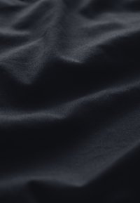 Dunkelblaues Gewebe mit einer glatten Textur, das sanfte, fließende Falten und einen subtilen Glanz im Licht zeigt.