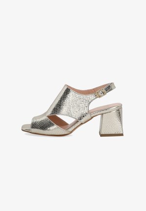 Metallic gold slingback heels with open toe, reptile texture, wide front cutouts, and a block heel. Buckle detail at the ankle.