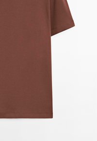 Bruin katoenen t-shirt met korte mouwen en een rechte snit, voorzien van een gladde textuur en nette stiksels langs de zoom en mouwen.