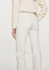 Witte op maat gemaakte broek met een gladde textuur, voorzien van een taillehoogte op het midden, achterzakken en een recht model, gecombineerd met een gestructureerde trui.