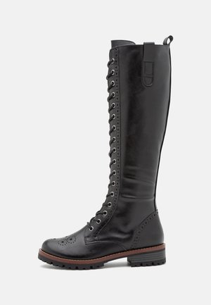 Botas de couro preto até ao joelho com um fecho de atacadores na frente, detalhes brogue e uma sola robusta. Apresenta um laço lateral para facilitar o calçar.