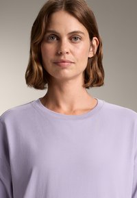 Felpa in cotone viola chiaro con collo rotondo e maniche lunghe, caratterizzata da una texture liscia e un fit rilassato.
