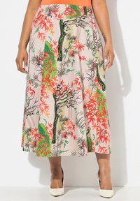 Une jupe mi-longue en tissu beige clair, ornée d'un imprimé floral et de paon vibrant en rouge, vert et noir. Texture lisse, design plissé.