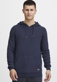 Sudadera azul marino de tejido suave con bolsillo canguro frontal, cordones ajustables y puños y dobladillo acanalados. Diseño liso.